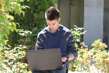 A student outside working on the computer